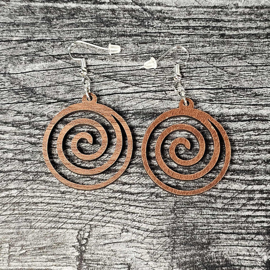 Walnut spiral earrings on a wooden surface