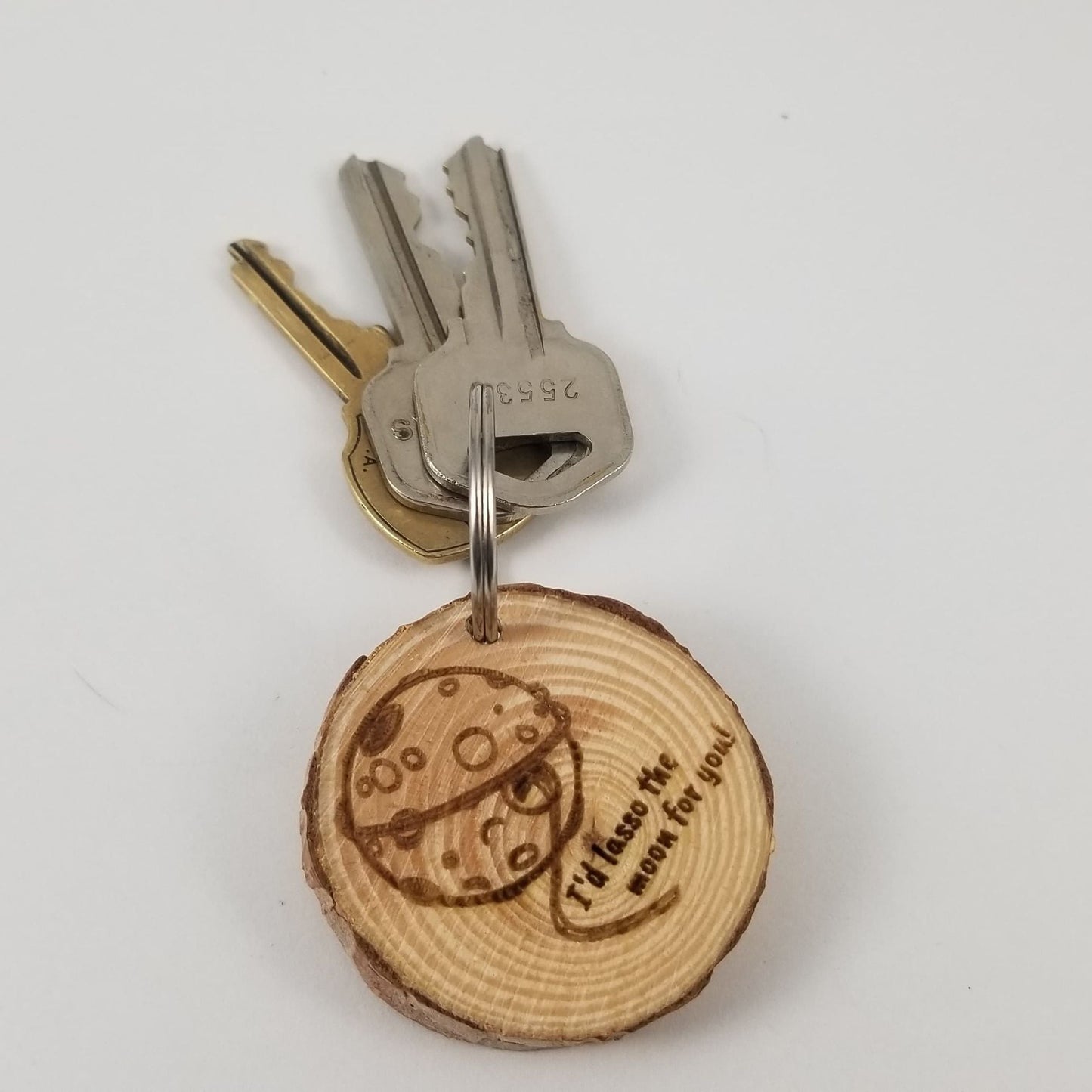 Wooden keychain with engraved design and text on a white background