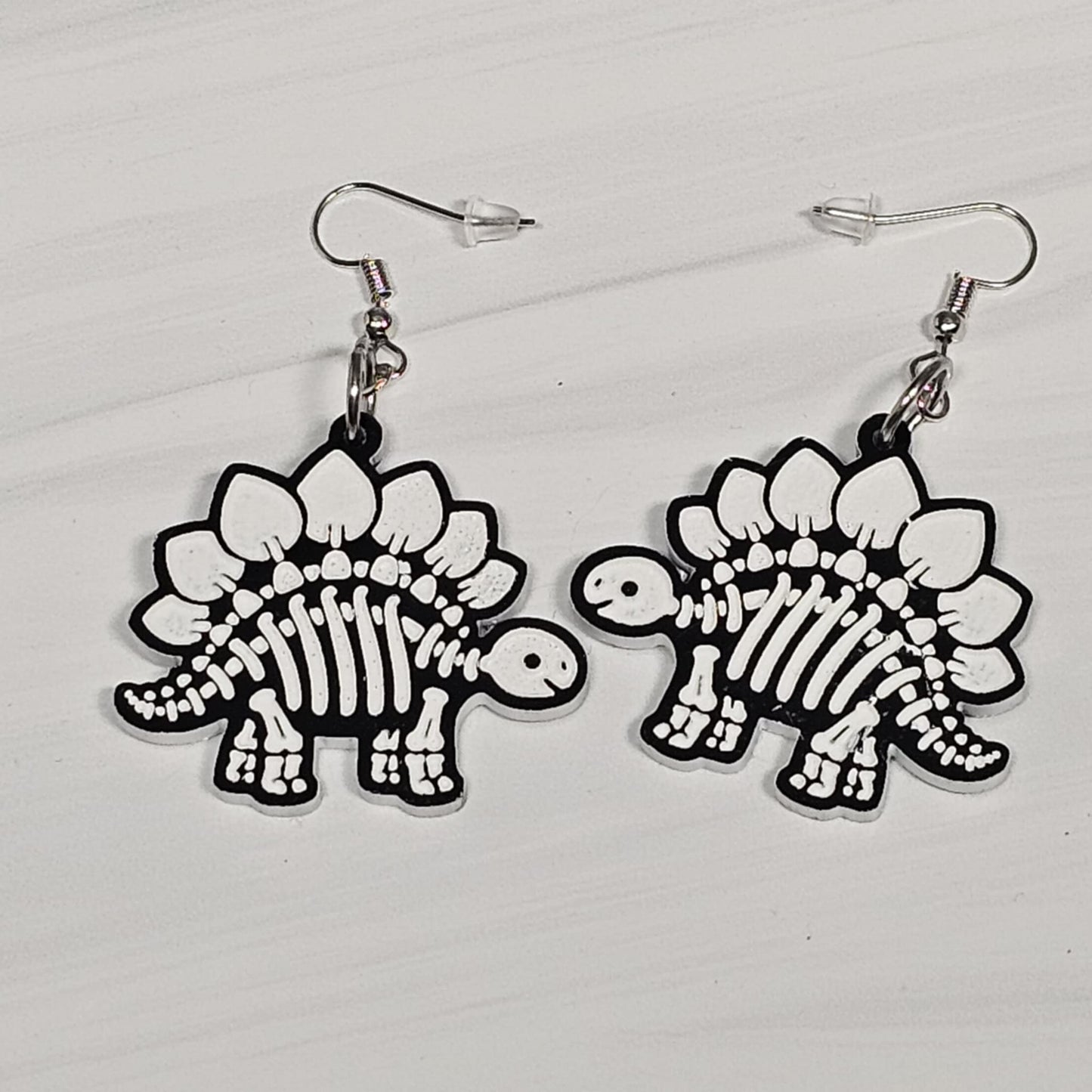 Dinosaur skeleton earrings on a light gray background