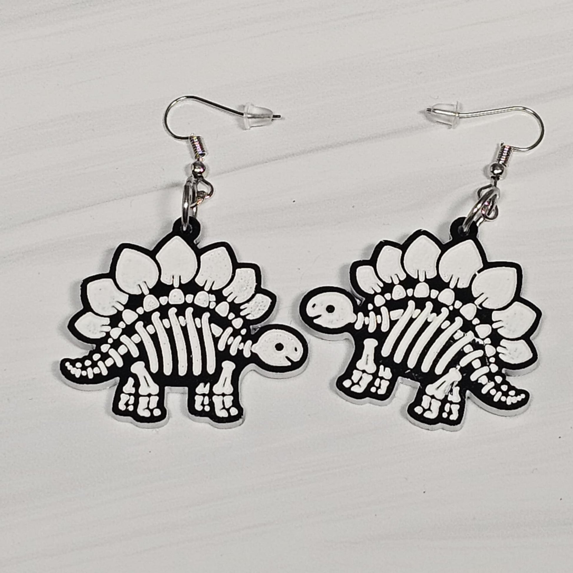 Dinosaur skeleton earrings on a light gray background