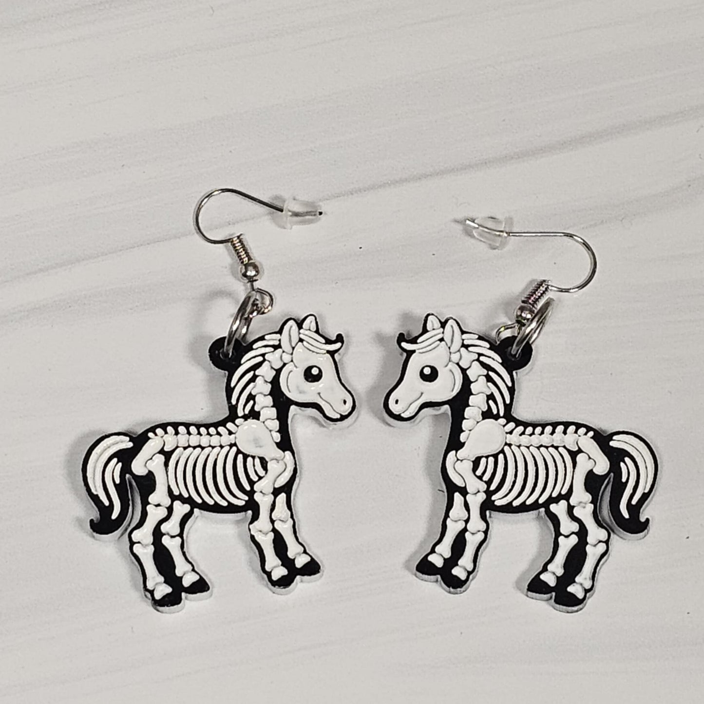 Horse skeleton earrings on a light gray background