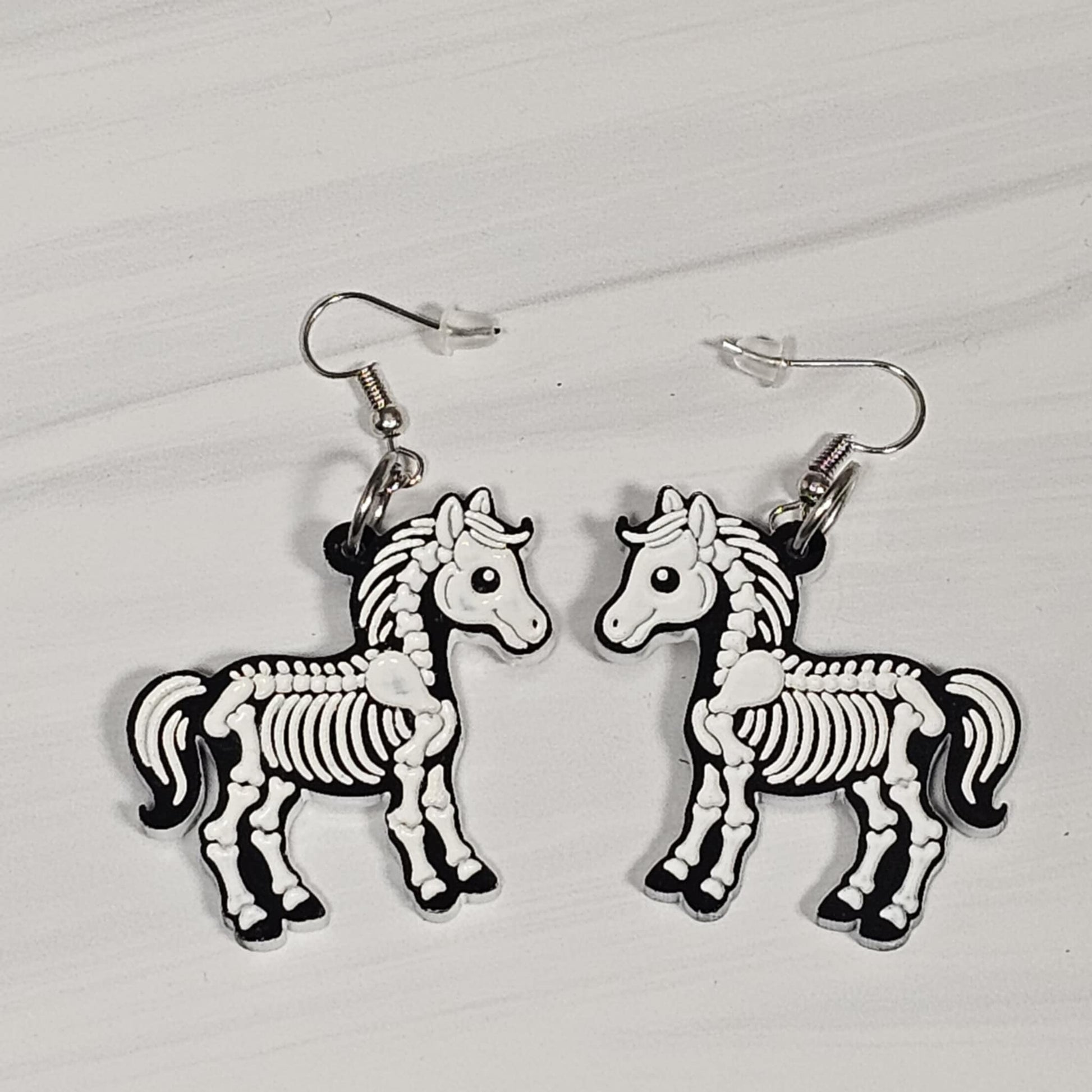 Horse skeleton earrings on a light gray background