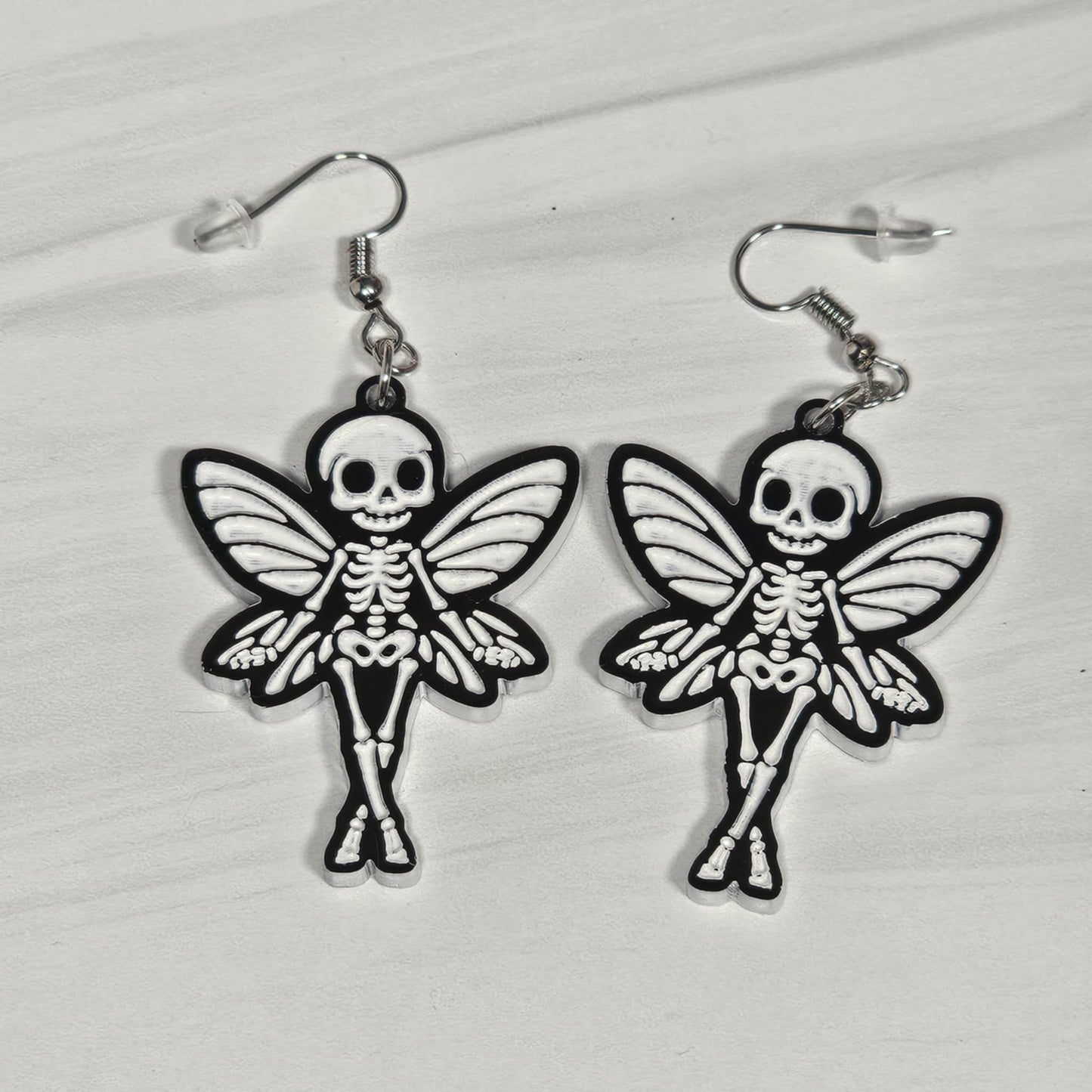 Skeletal fairy earrings on a light gray background