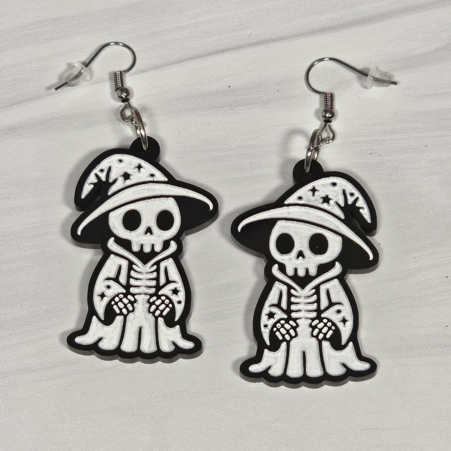 Pair of wizard skeleton earrings with hats on a light gray background
