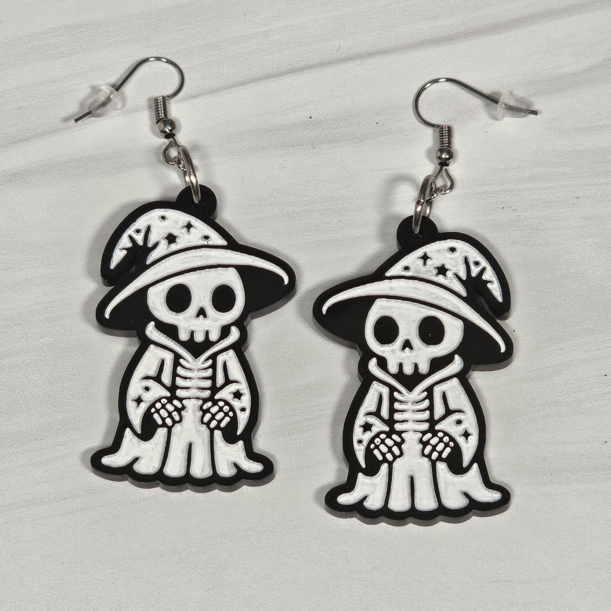 Pair of wizard skeleton earrings with hats on a light gray background