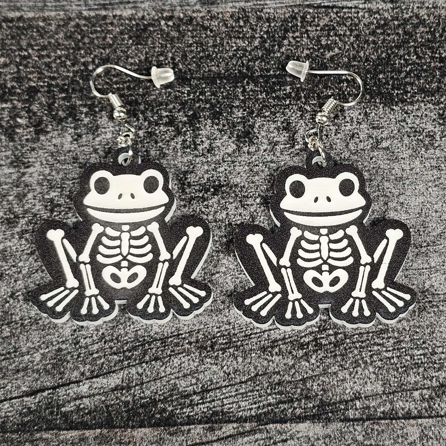 Frog skeleton earrings on a wooden surface