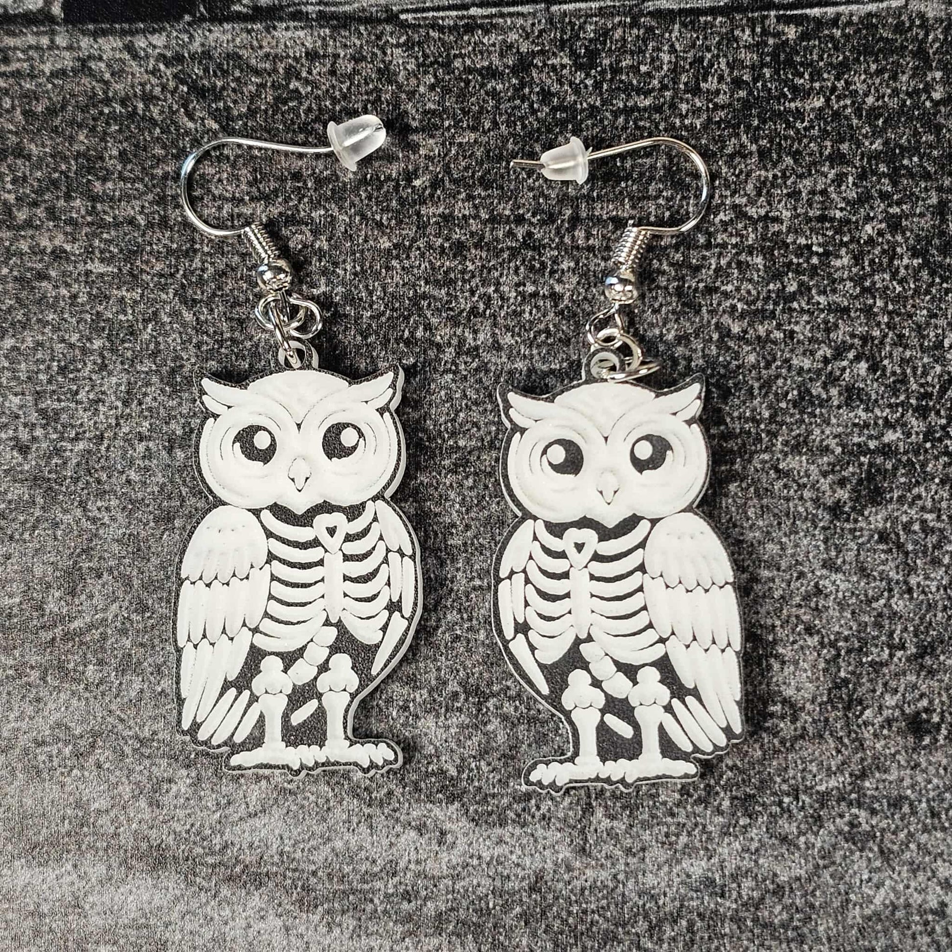 Owl skeleton earrings on a textured surface