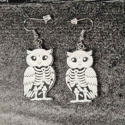 Owl skeleton earrings on a textured surface