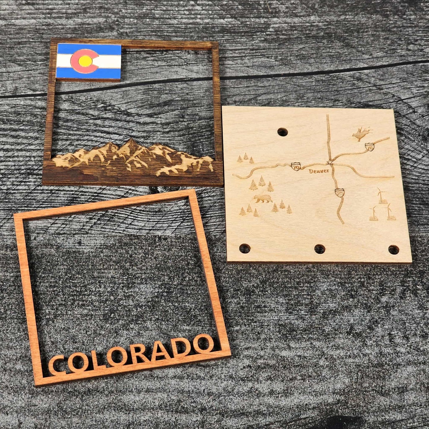 Wooden decorative items with mountain design, map, and 'Colorado' text on a wooden surface.