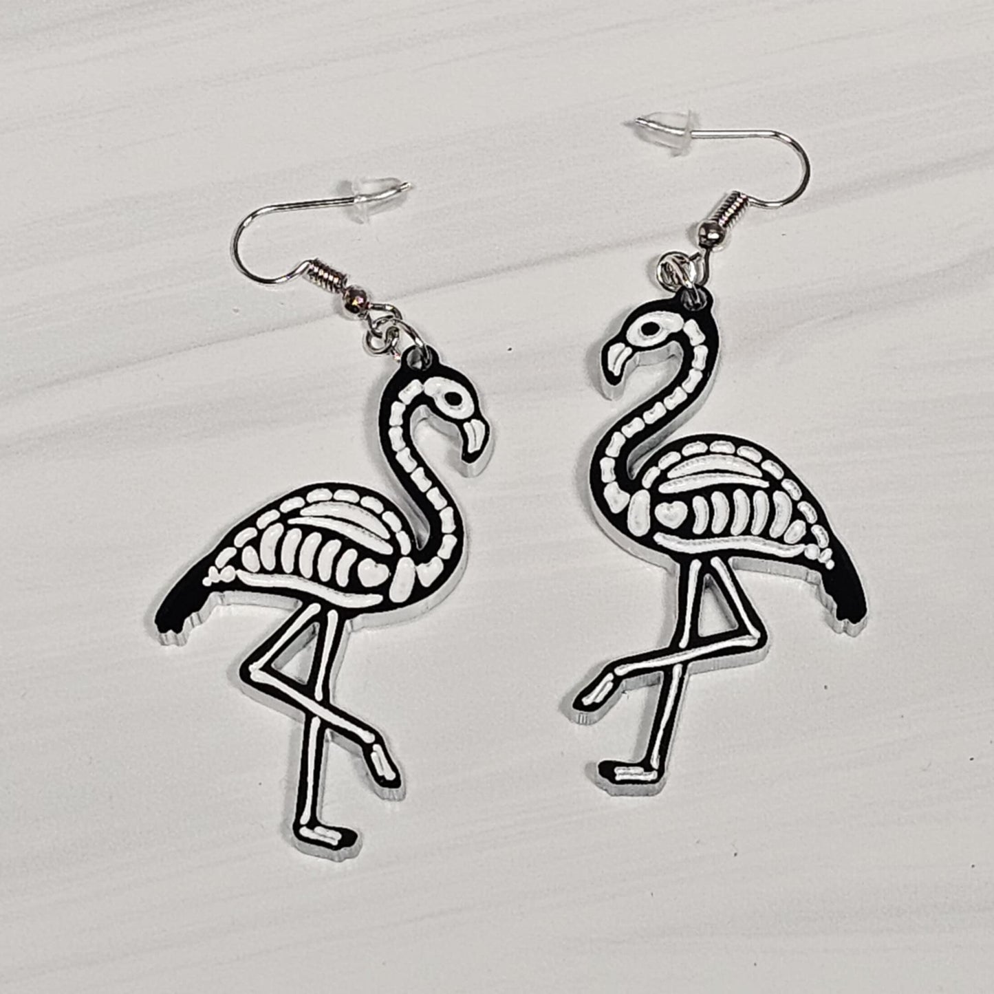 Flamingo skeleton earrings on a light gray background