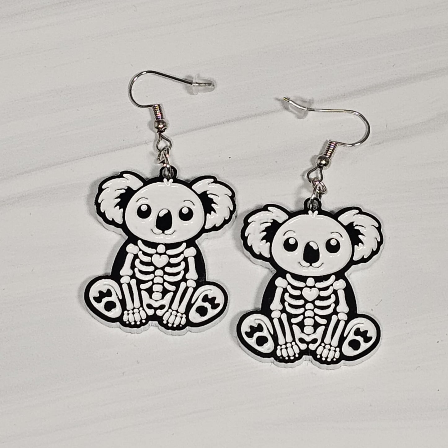 Skeletal koala bear earrings on a light gray background