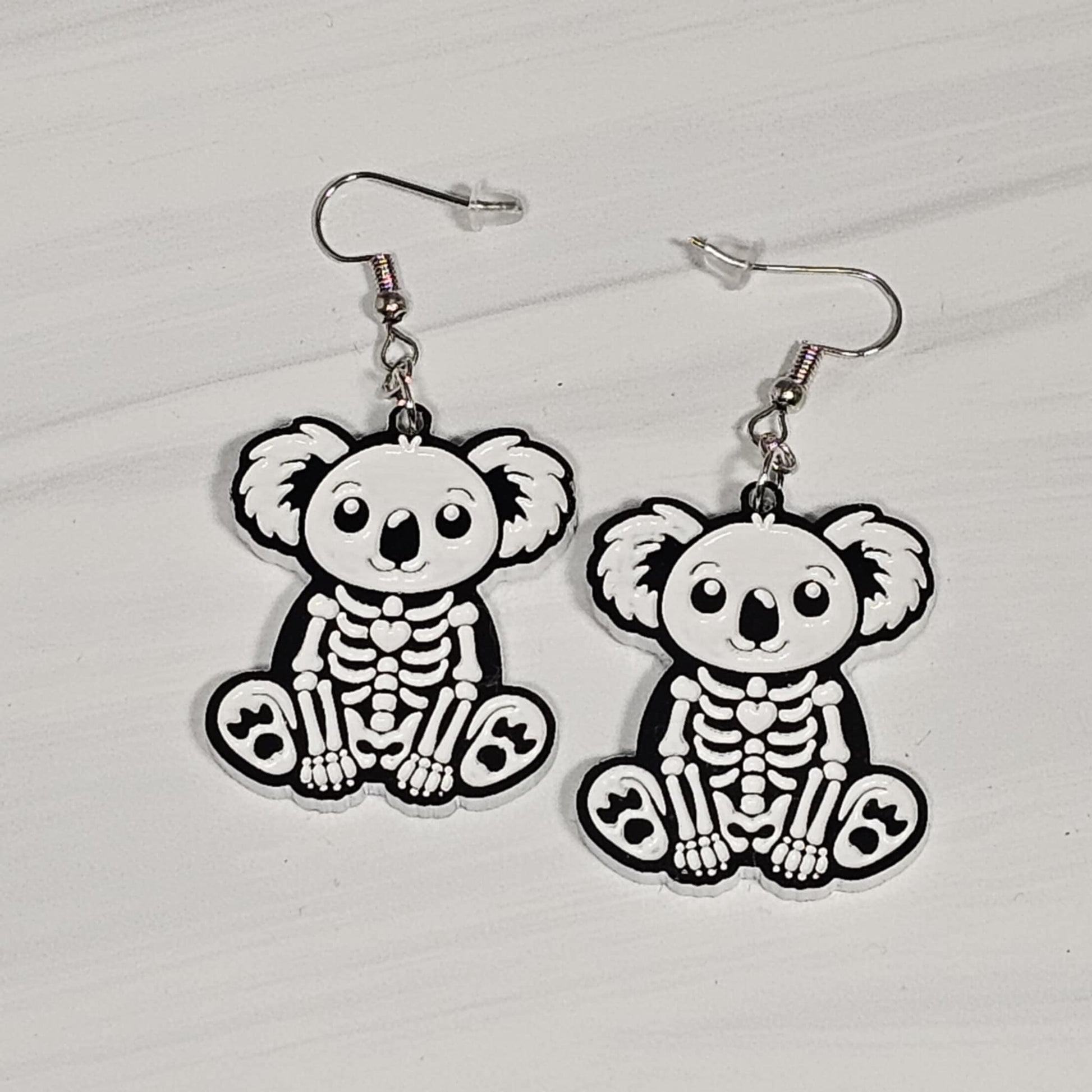 Skeletal koala bear earrings on a light gray background