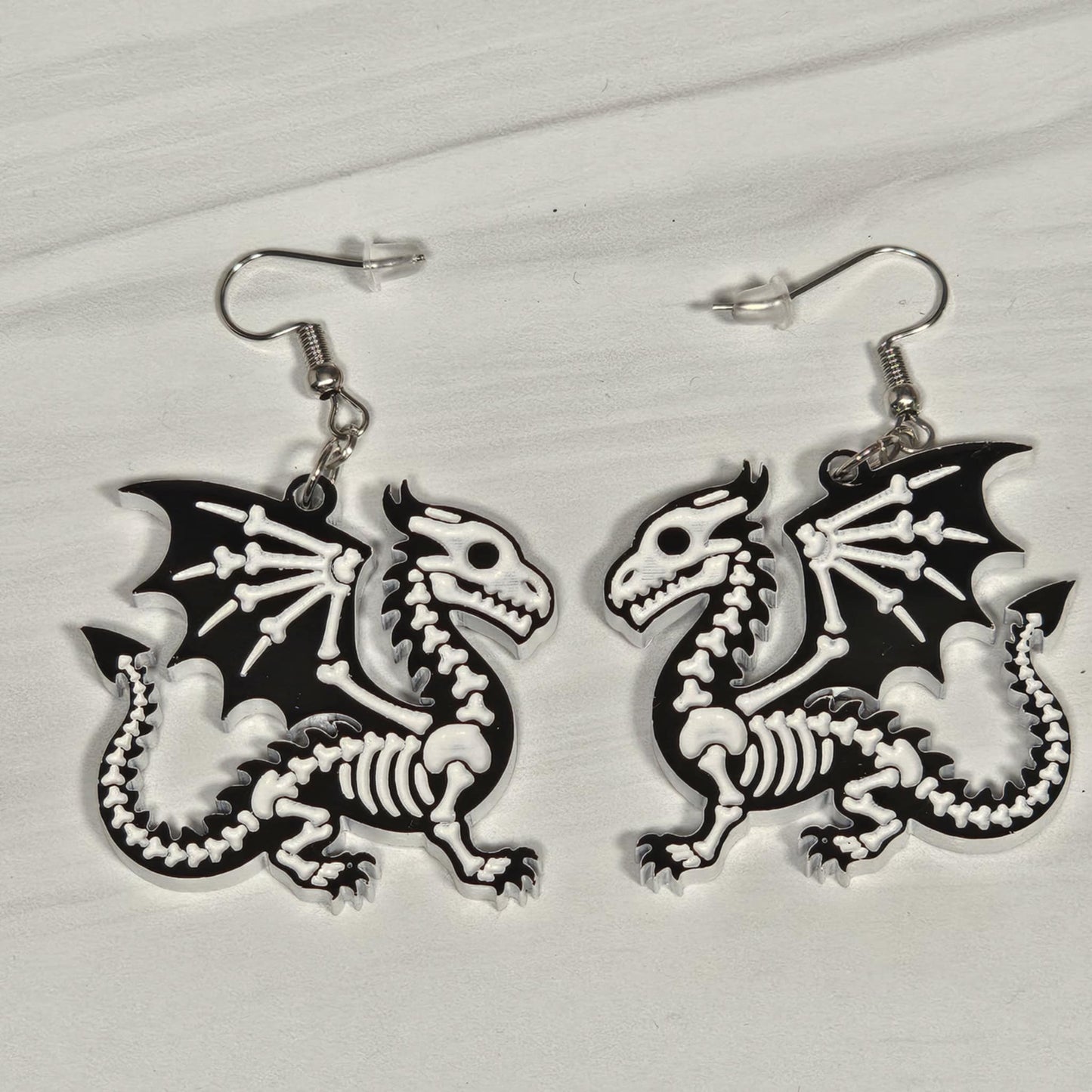 Dragon skeleton earrings on a light gray background