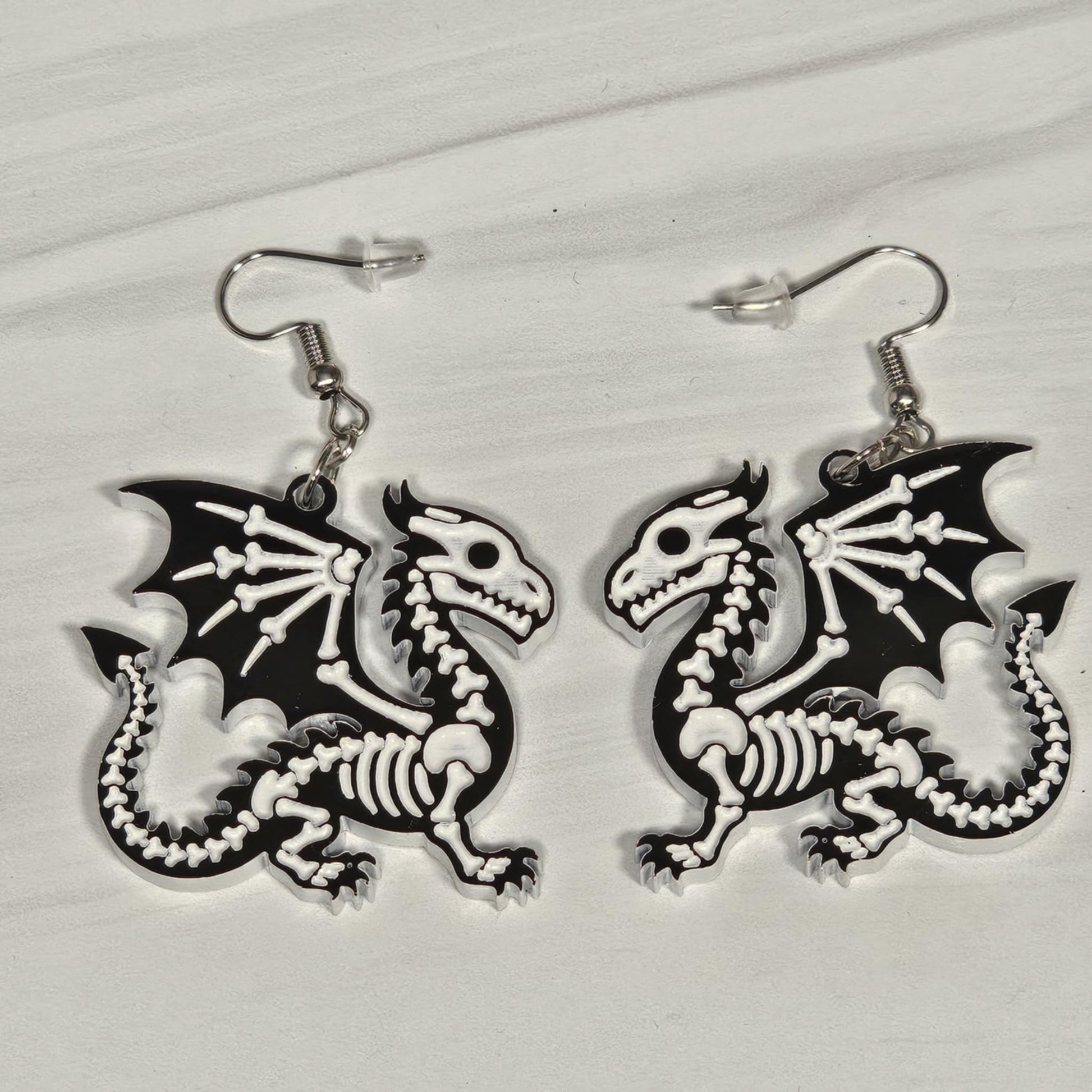 Dragon skeleton earrings on a light gray background