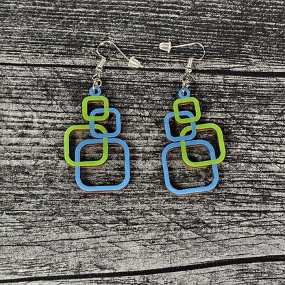 Pair of blue and green square-shaped earrings on a wooden surface.  The squares alternate blue and green.