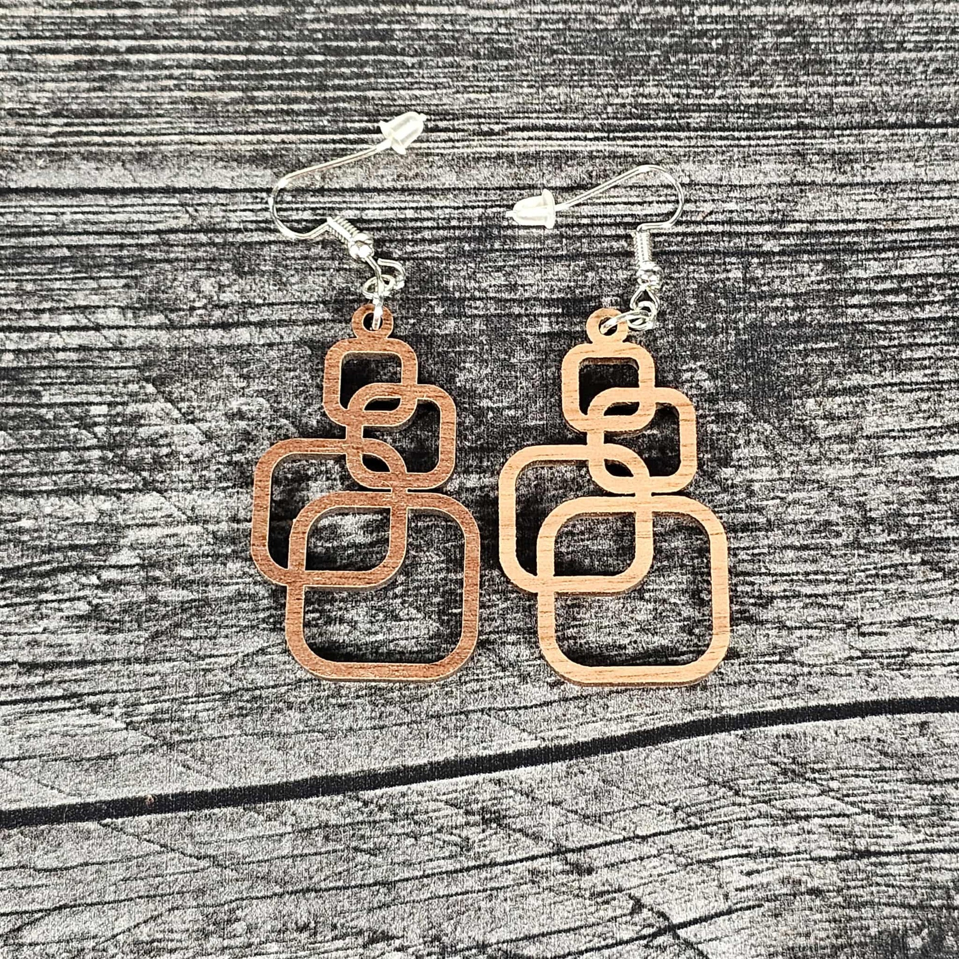 Pair of geometric earrings on a wooden surface.  Walnut and cherry color options shown