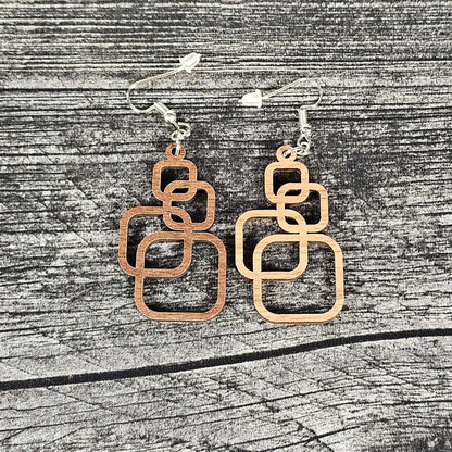 Pair of geometric earrings on a wooden surface.  Walnut and cherry color options shown