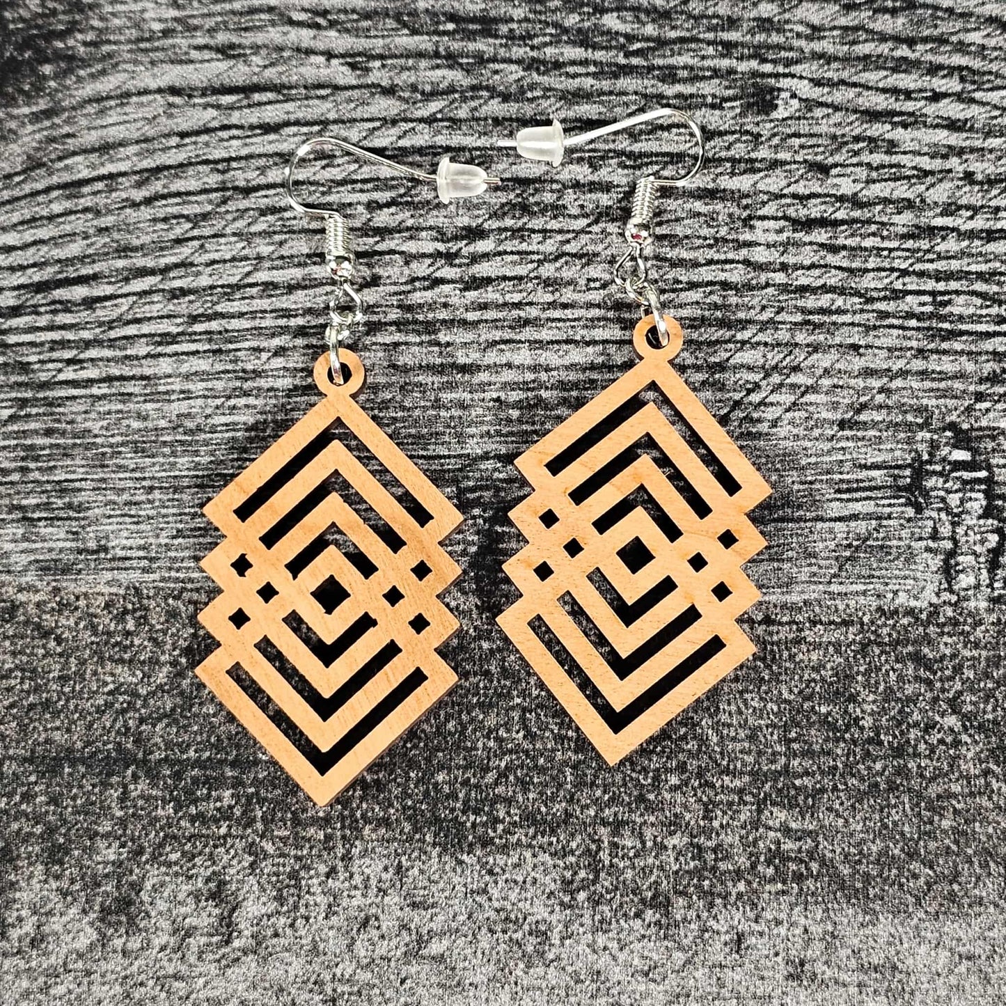 Cherry wood geometric diamond patterned earrings on a textured gray surface