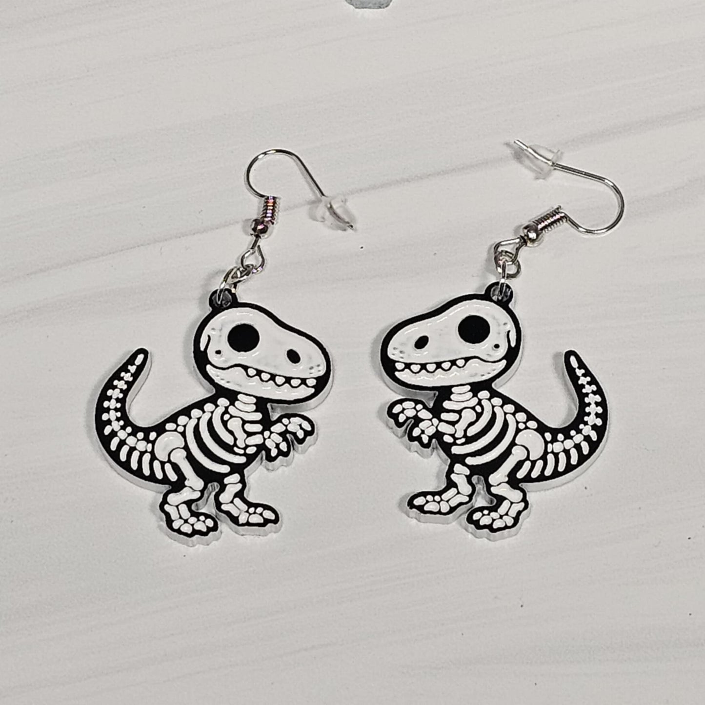 T-Rex skeleton earrings on a white background