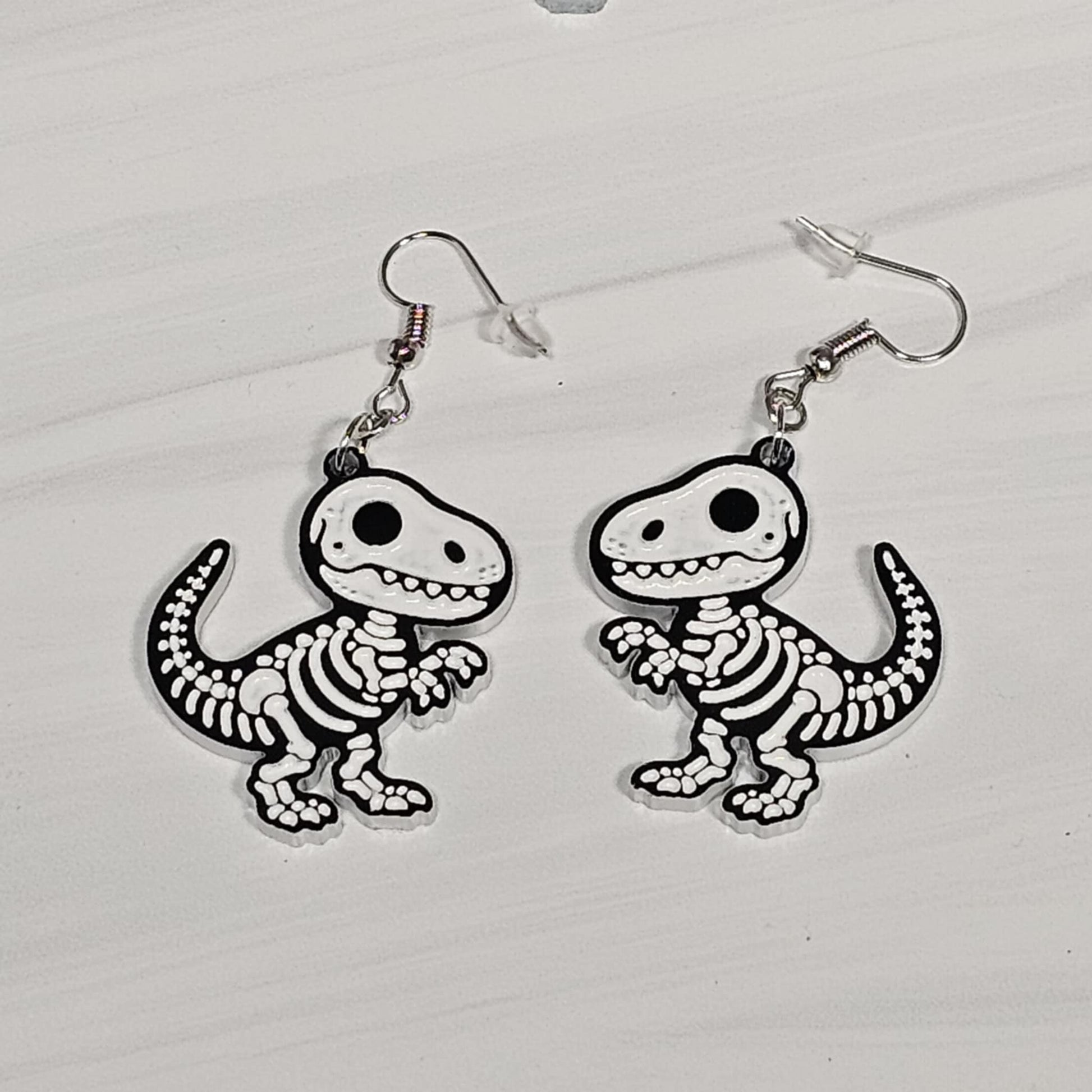 T-Rex skeleton earrings on a white background