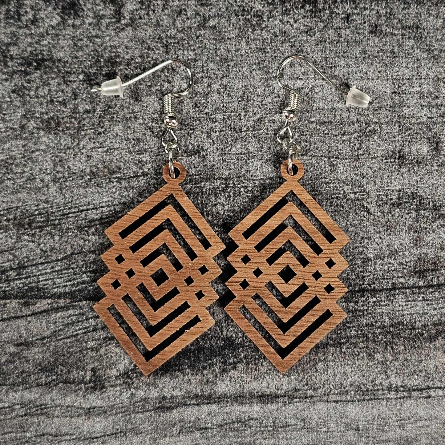 Walnut wood geometric diamond patterned earrings on a textured gray surface