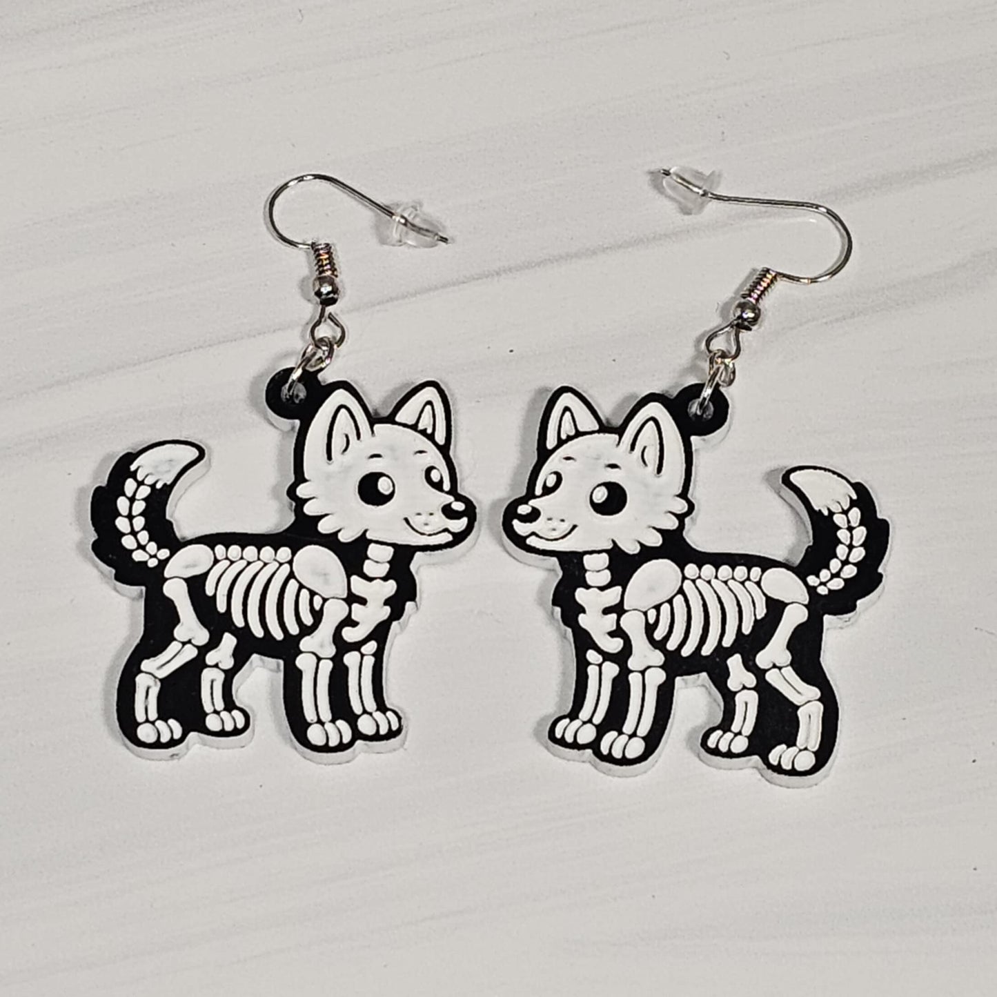 Pair of wolf skeleton earrings on a white background