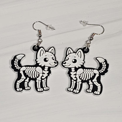 Pair of wolf skeleton earrings on a white background