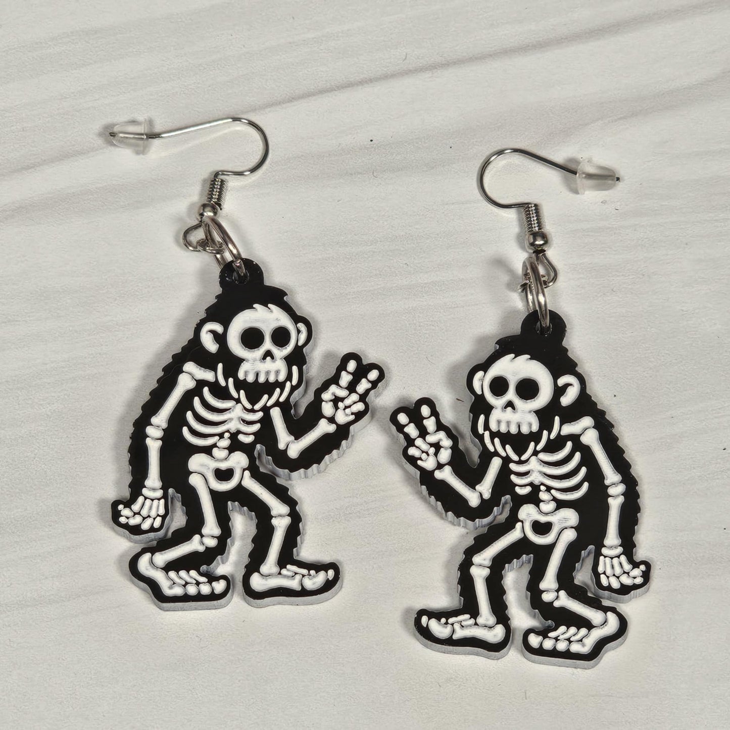 Skeleton bigfoot earrings on a light gray background