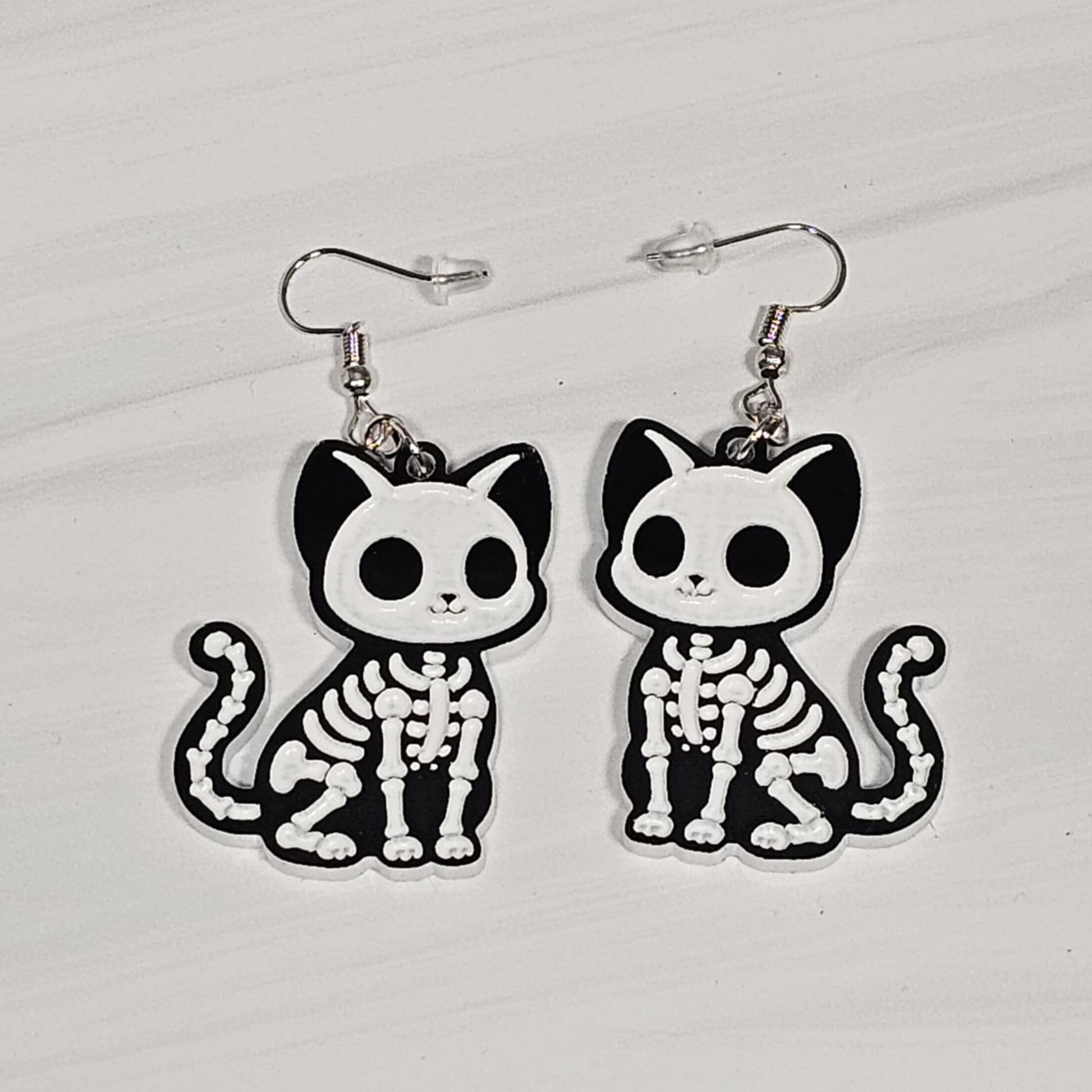 Cat skeleton earrings on a white background