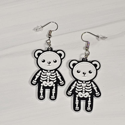 Pair of skeleton teddy bear earrings on a light gray background