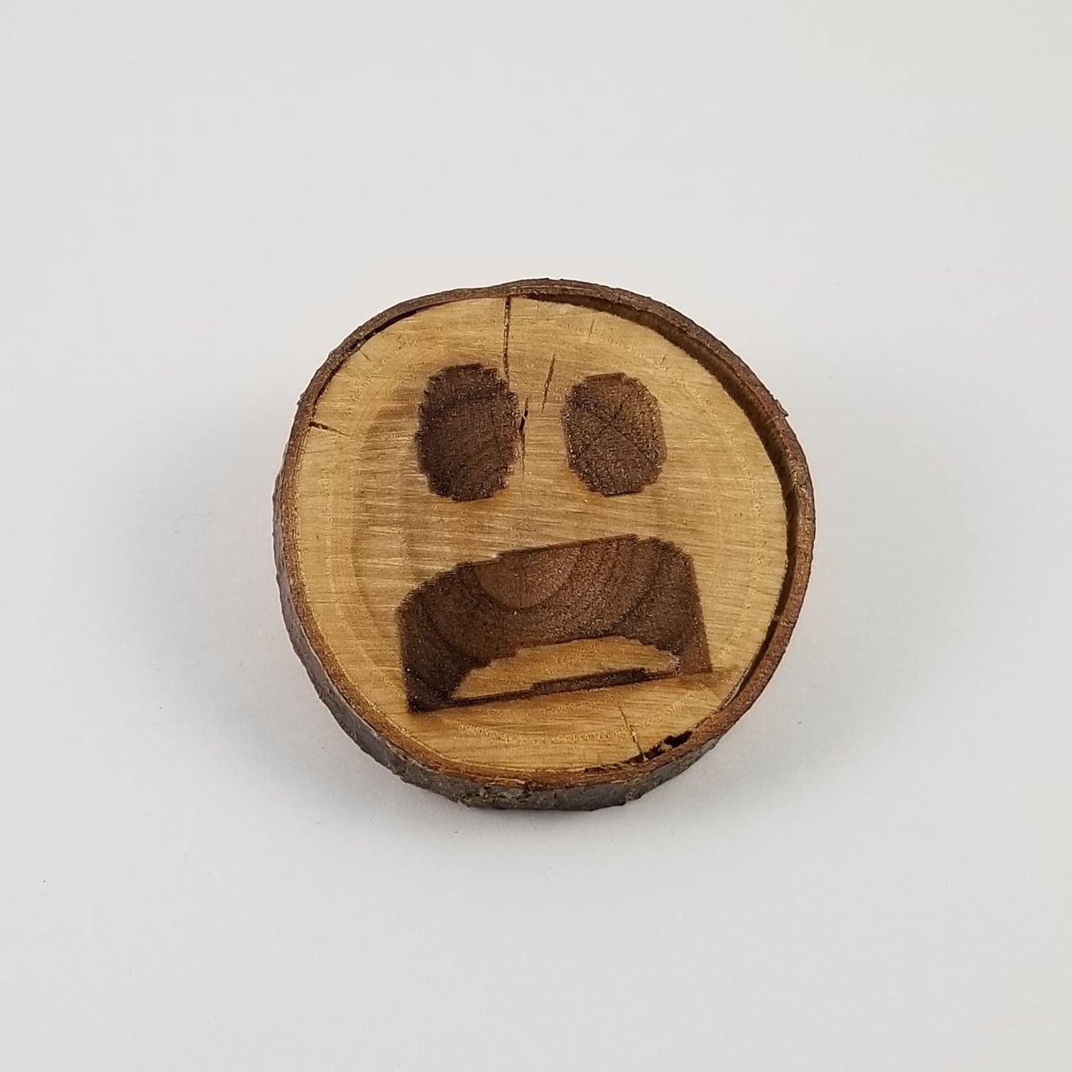 Wooden emoji with a sad expression on a white background