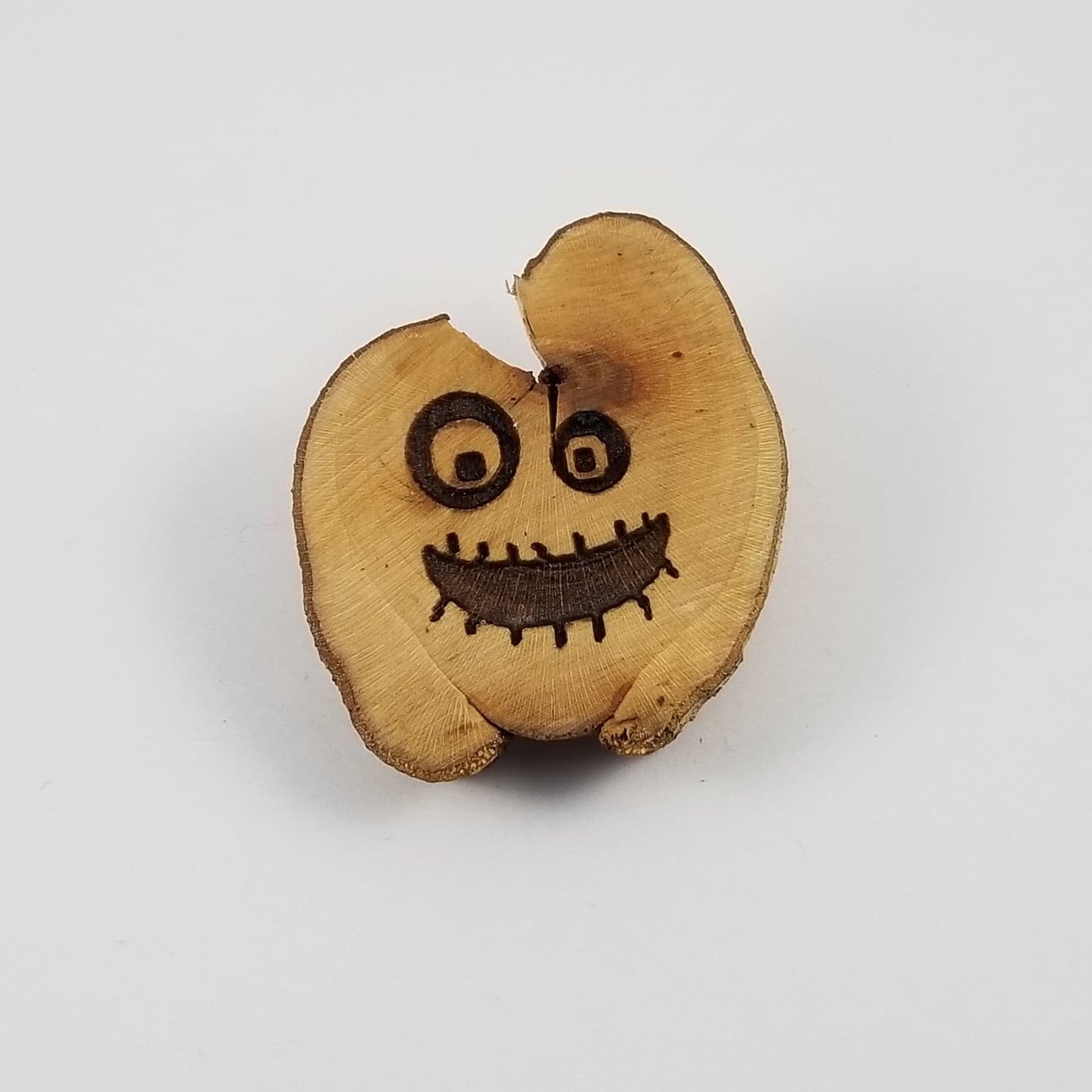 A wooden mail slot in the shape of a smiling face with two faces, one on each side, carved on a wooden post.