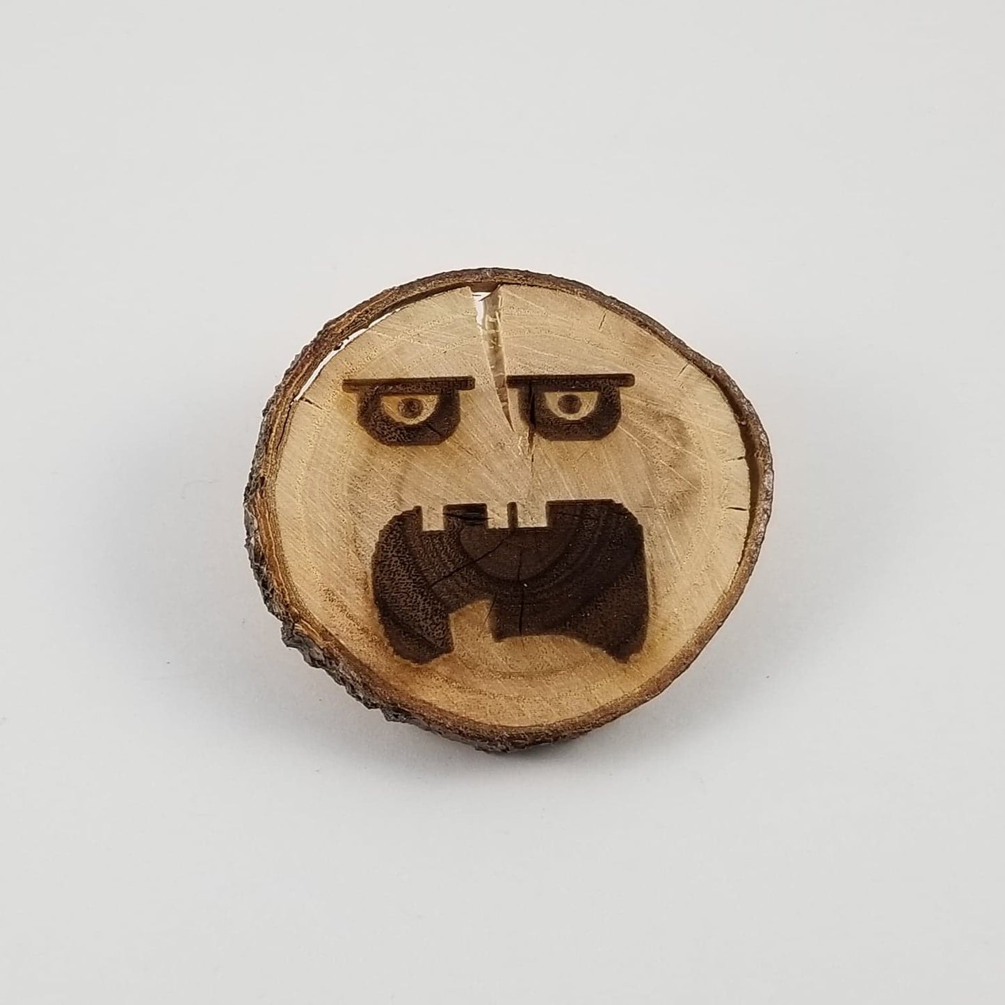 Wooden slice with a carved face design on a white background