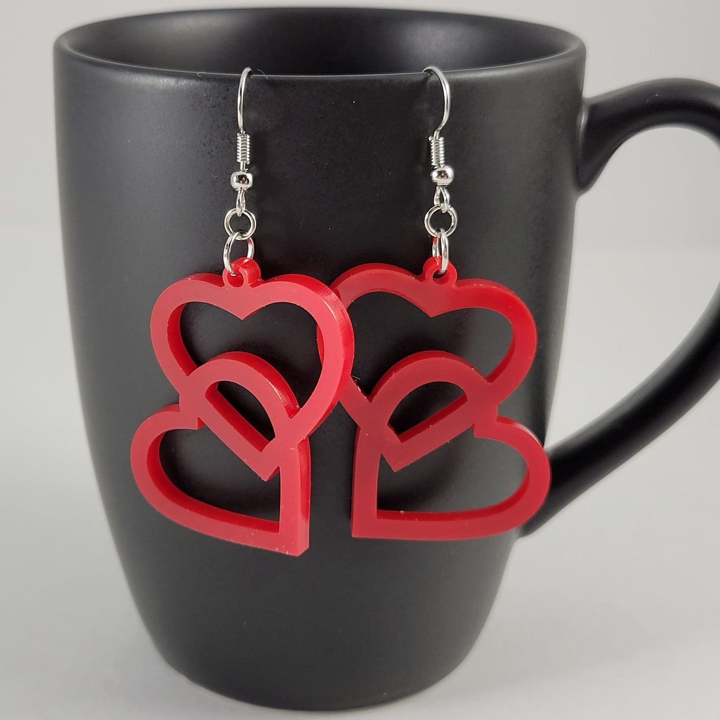 Red heart-shaped earrings on a black mug