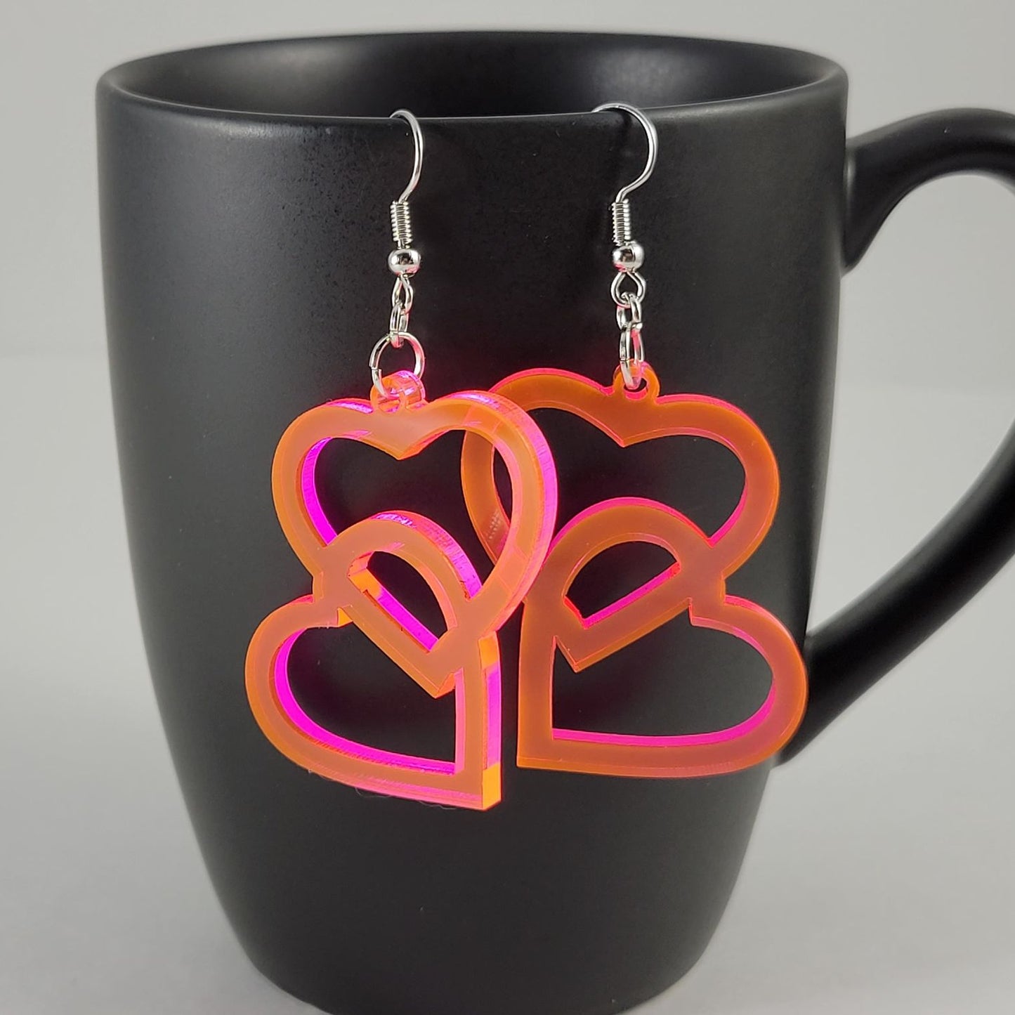 Heart-shaped earrings on a black mug