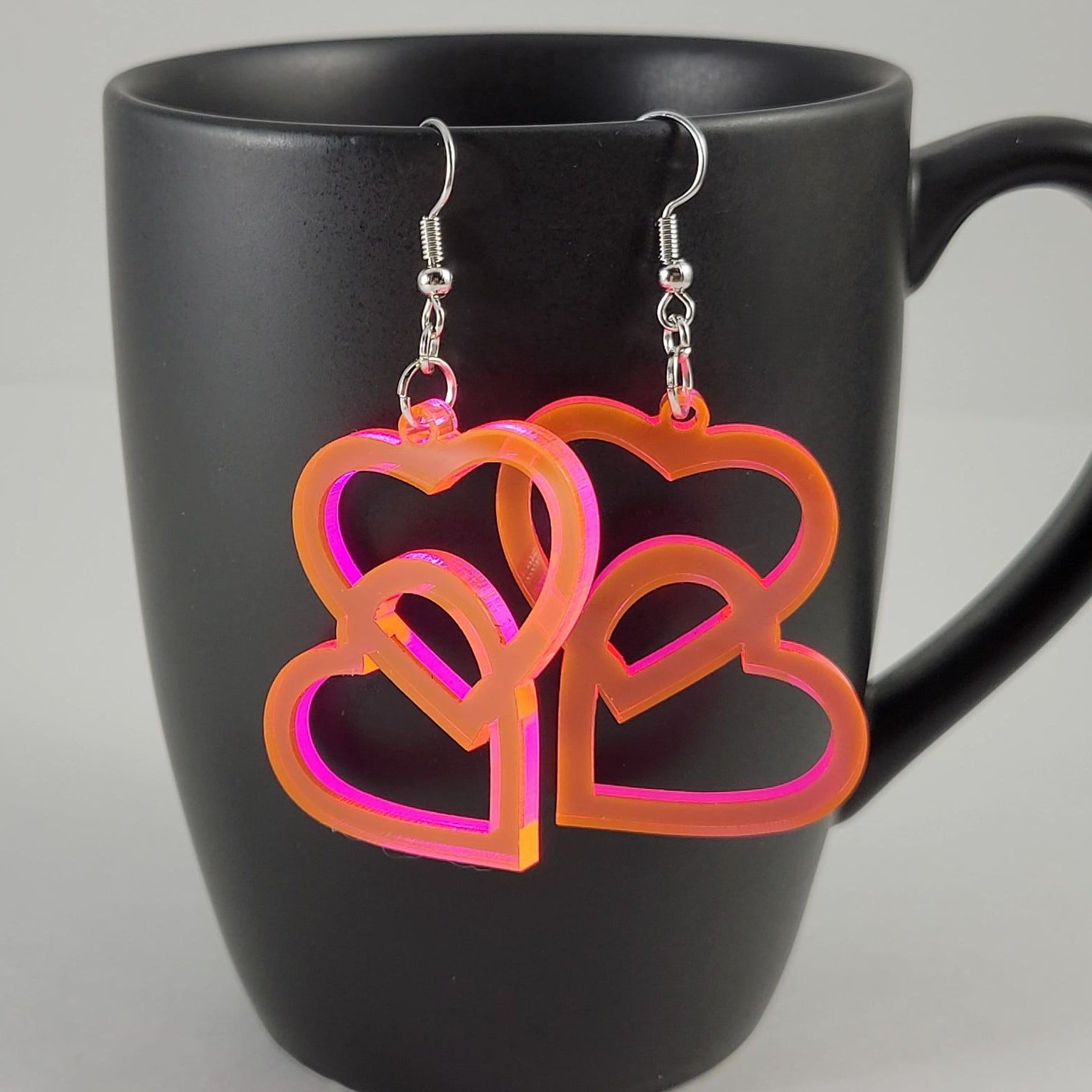 Heart-shaped earrings on a black mug