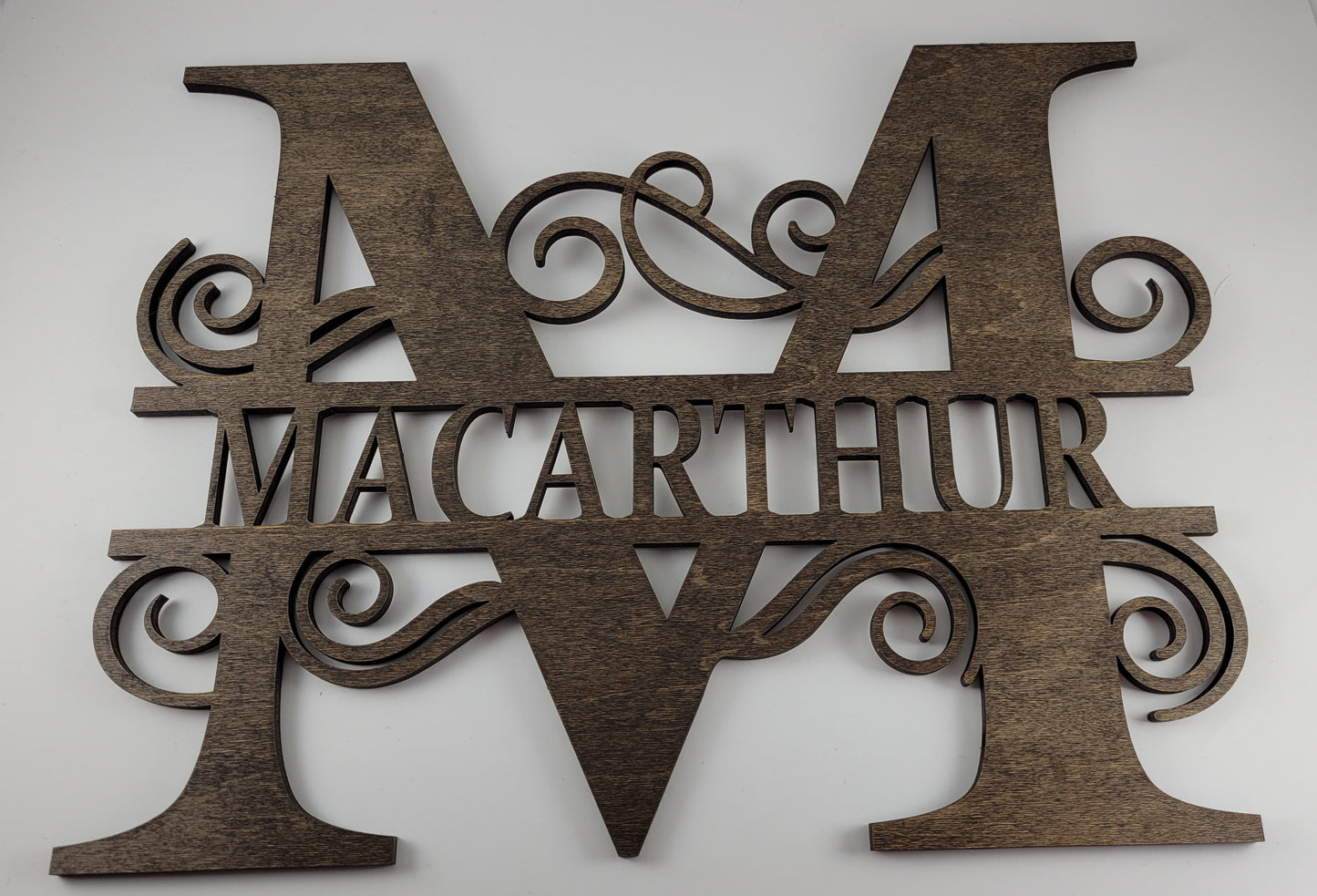 A brown wooden monogram with swirls, cut out of maple, with the letter 'M' prominently displayed.
