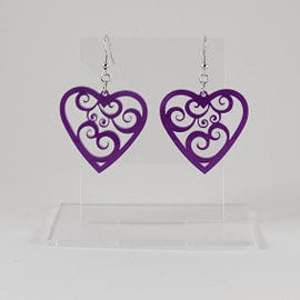 A pair of purple swirly heart earrings with silver hooks and a silicone backing, displayed in a clear case.