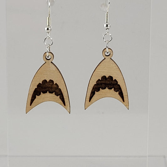 A pair of wooden earrings designed to resemble shark fins, with silver hooks and silicone backing, displayed on a clear stand.