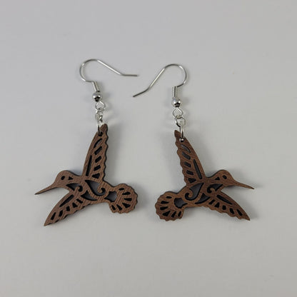 A pair of brown walnut hummingbird earrings with silver fish hooks and silicone backing.