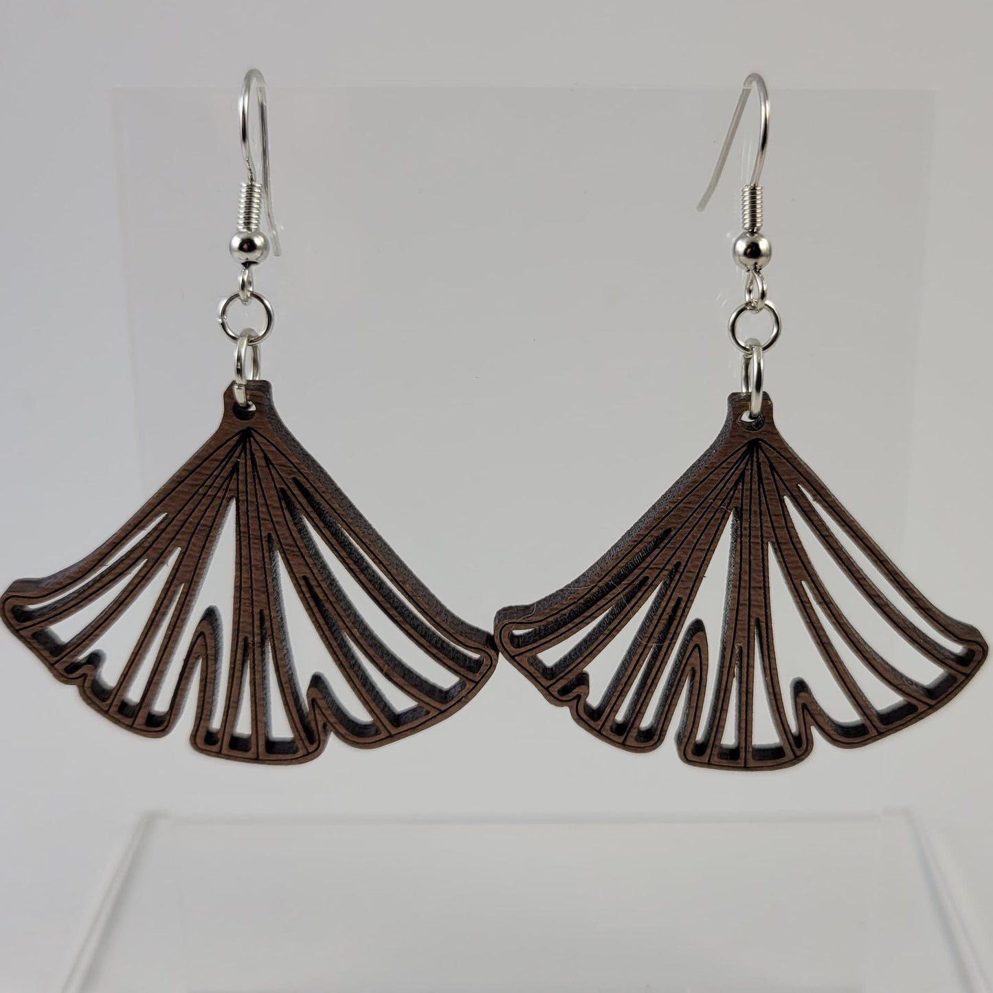 A pair of brown ginkgo leaf-shaped earrings with silver hooks and a silicone backing, displayed against a white background.