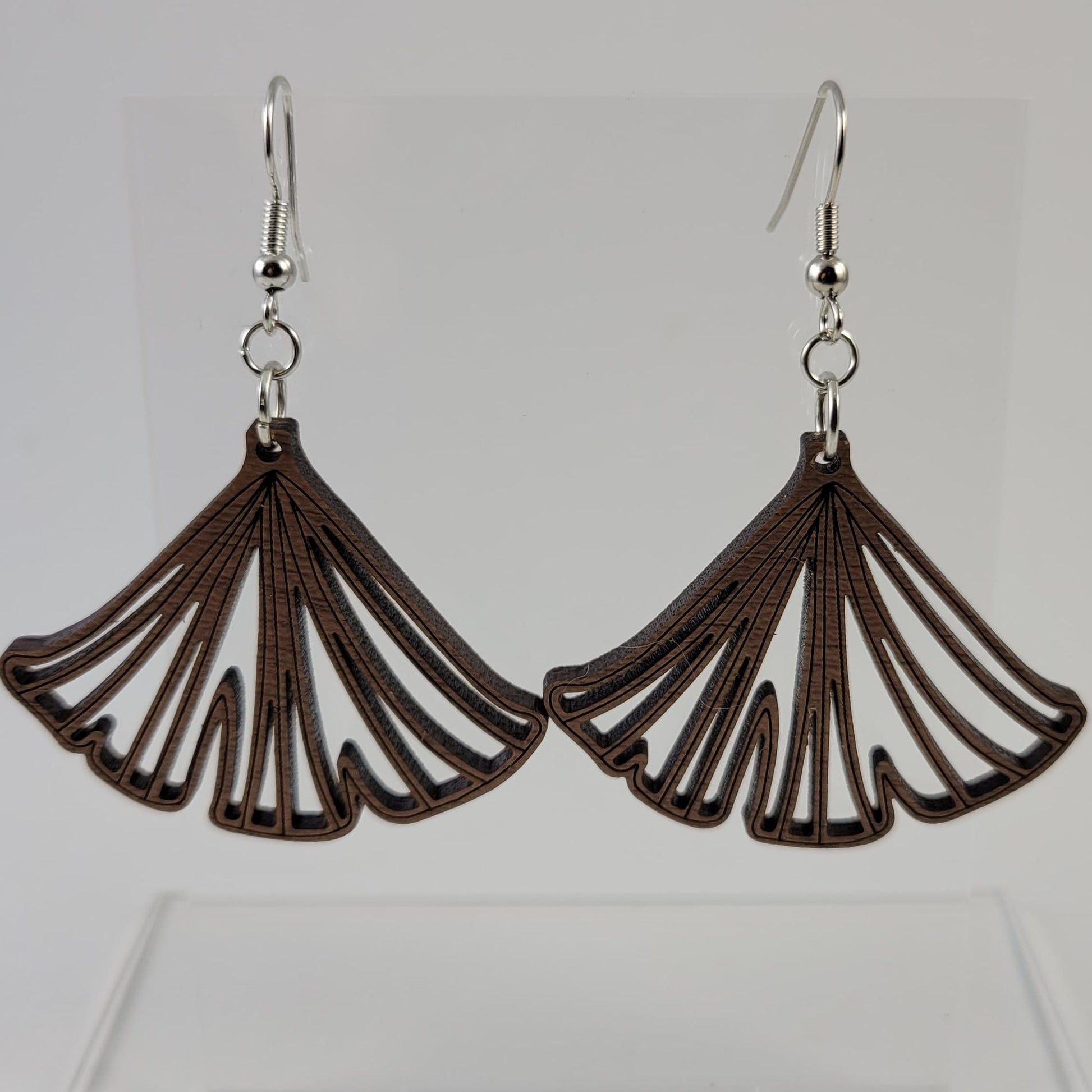 A pair of brown ginkgo leaf-shaped earrings with silver hooks and a silicone backing, displayed against a white background.