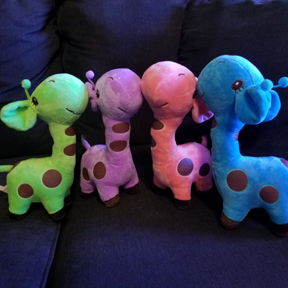 A set of four plush giraffe toys in different colors placed on a couch, with a focus on their cute and friendly design.