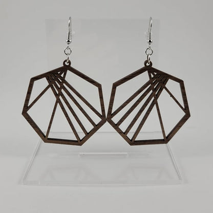 A pair of brown geometric heptagon earrings made of walnut wood, with silver fish hook settings and a silicone backing, displayed on a clear stand.