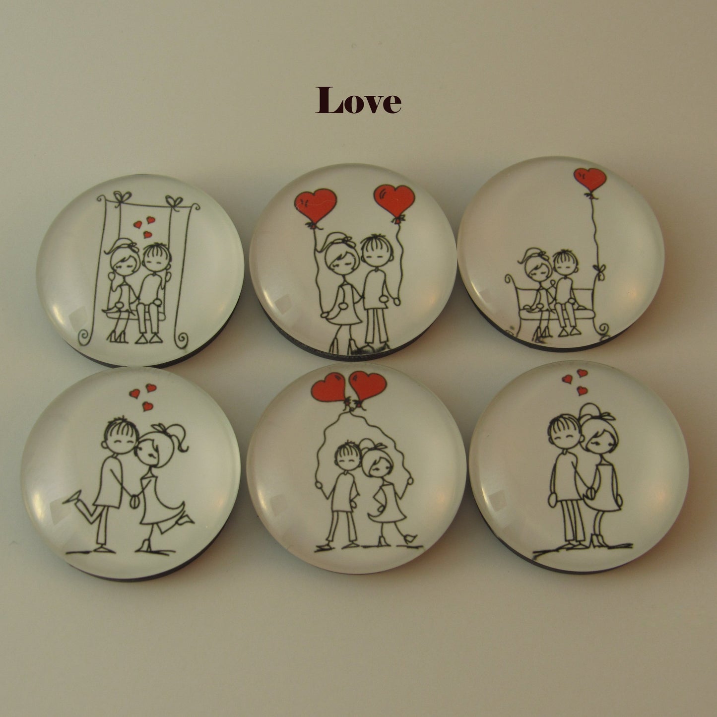 Set of six decorative buttons with romantic illustrations and 'Love' text on a beige background