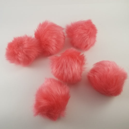 Six pink fluff balls arranged on a white background, with a teal heart bag with a drawstring in the center.